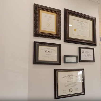 Framed diplomas and certifications on the office wall